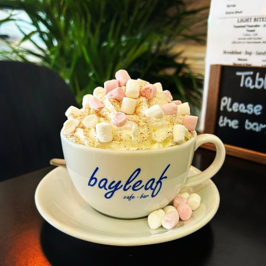 A hot chocolate piled with pink and white marshmallows in a white cup printed bayleaf cafe · bar